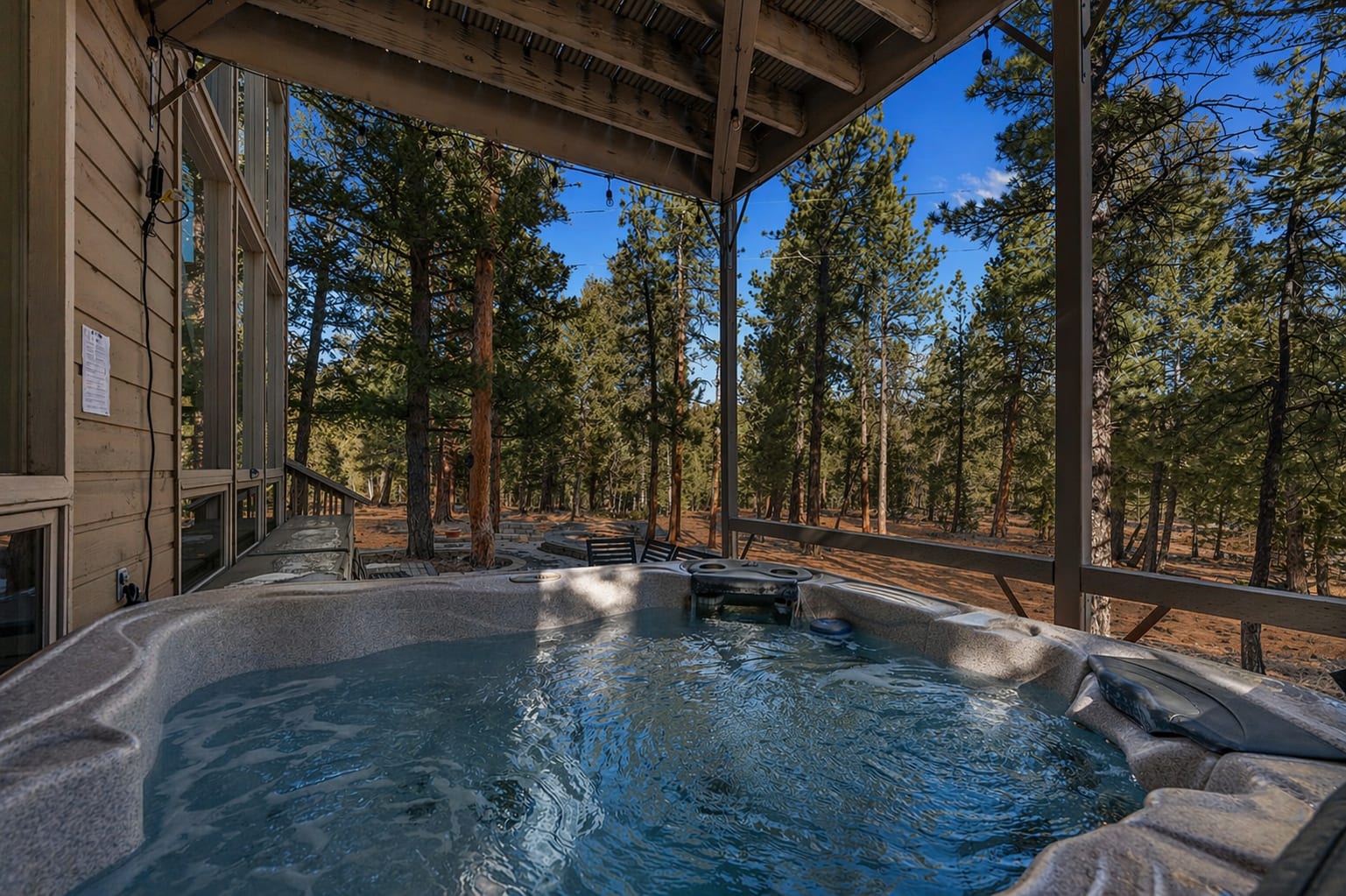Private hot tub under the deck surrounded by pine forest