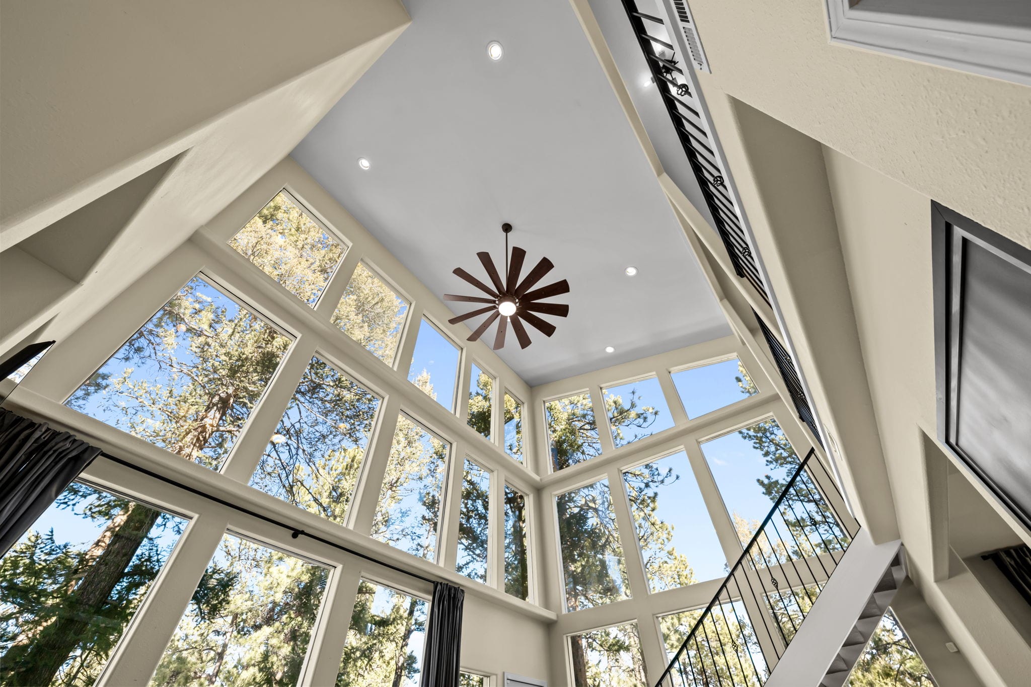 Two-story living room windows framing the surrounding pine forest