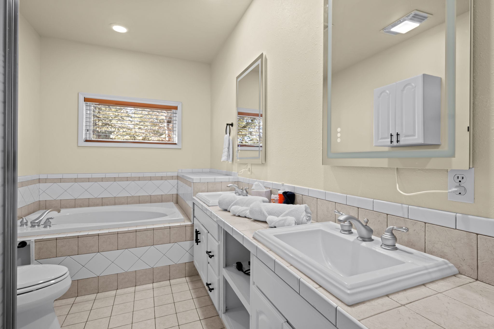 Bathroom with bathtub, double sinks and window